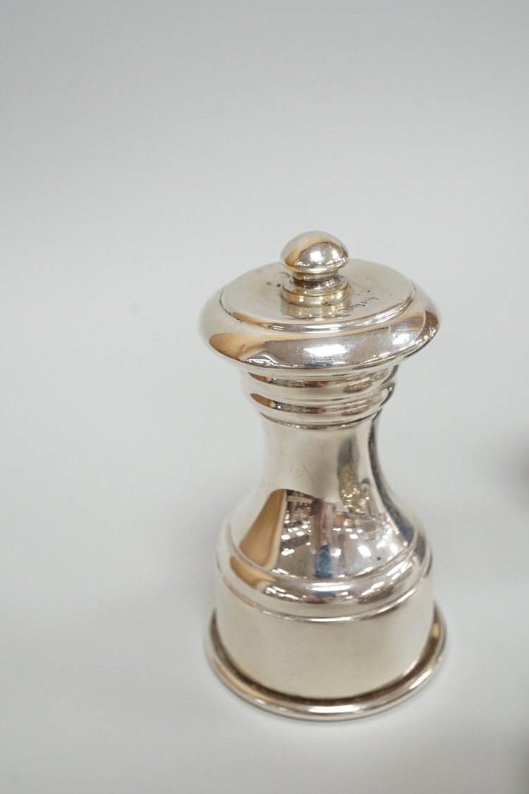 Four assorted silver condiments including a Victorian bun salt and a late Victorian pepper mill, together with a small silver bowl, a silver matchbox sleeve and a small silver two handled cup.